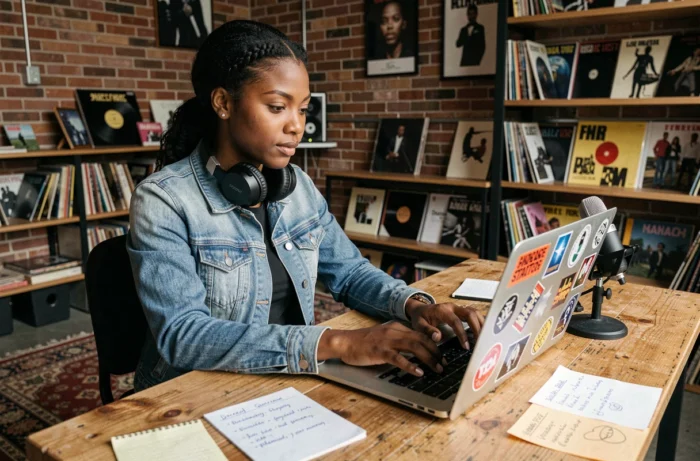 Jeune artiste musicale construisant sa marque dans un studio indie avec un laptop et des vinyles
